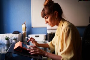 Side view of a confident graphic designer sitting at her desk working on her digital tablet.