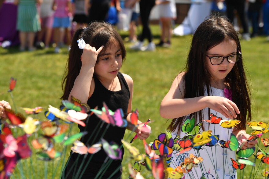 Riverside first graders Julianna Stull and Samira Khandi pick out butterflies from the Northeast Suicide Prevention Initiative board.